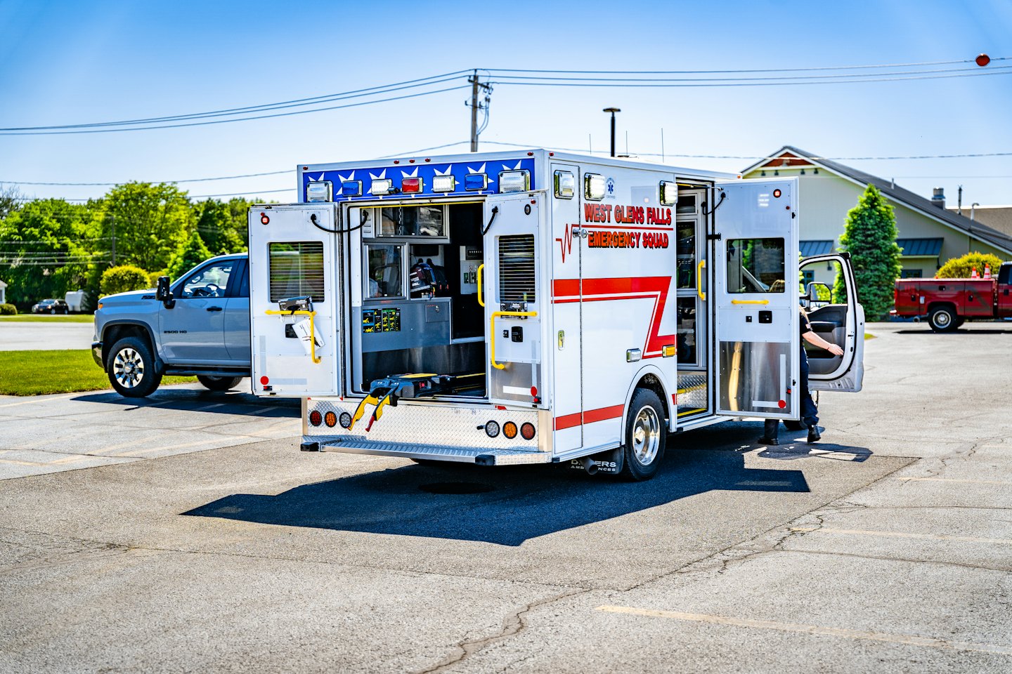 Emergency ambulance with open doors parked in a paved lot.